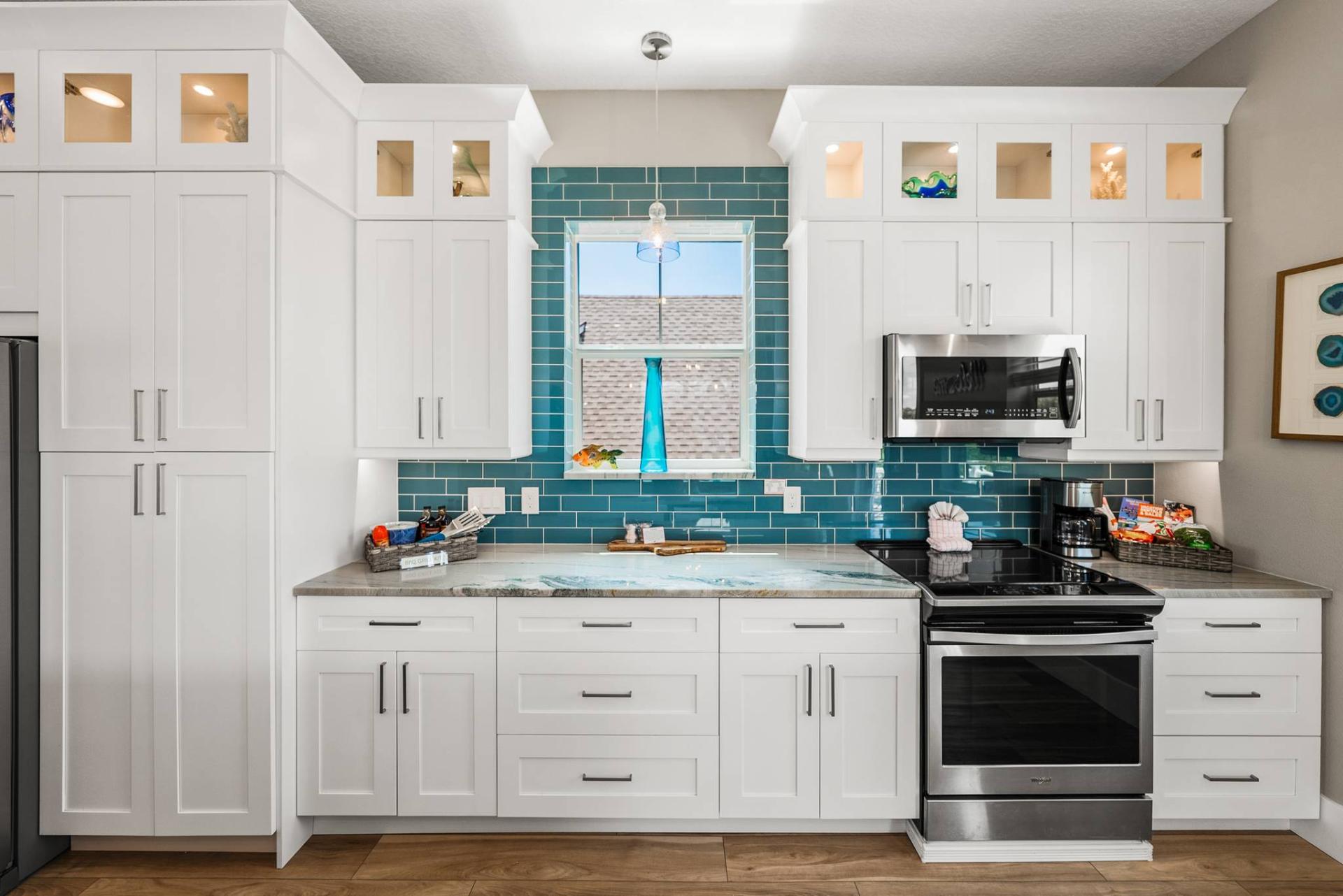 Kitchen window framed by teal subway tile