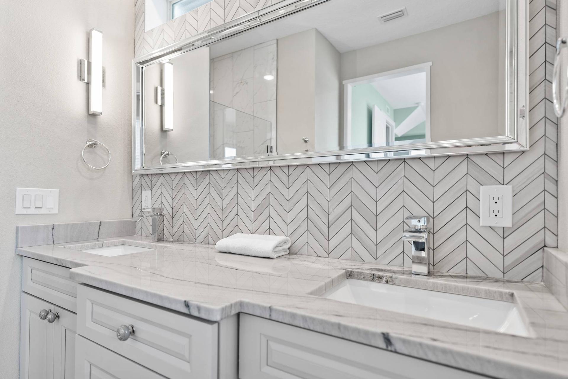 Marble double-vanity bathroom detail with chevron backsplash