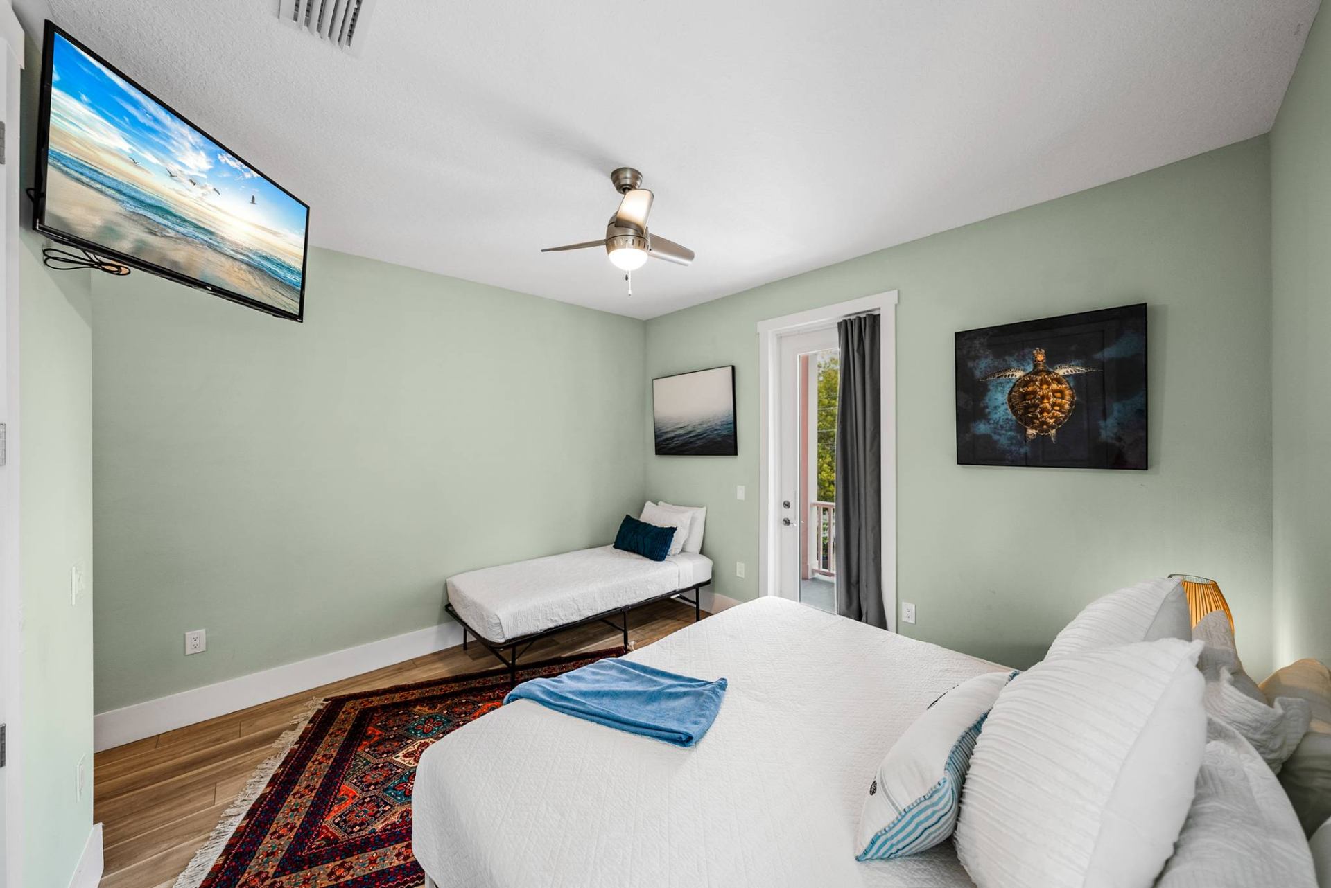Guest bedroom with TV, daybed, and balcony door